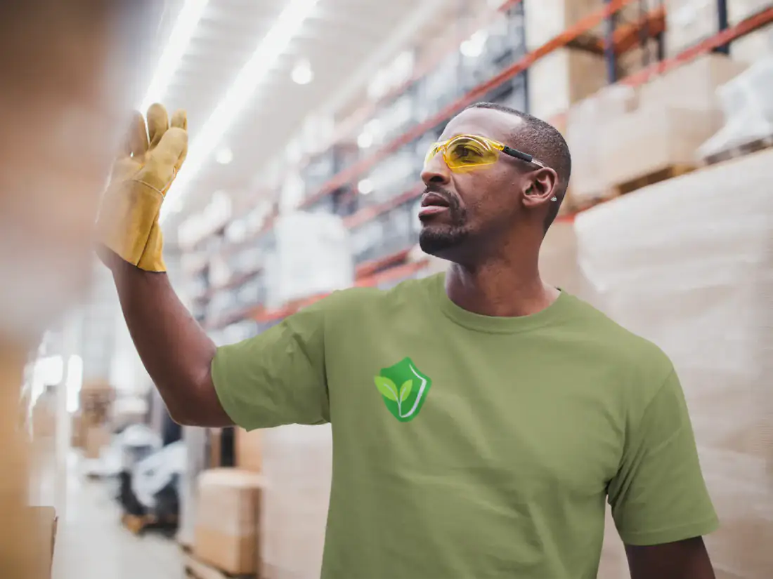 A worker in a Crop Compliance shirt and safety glasses in a packhouse